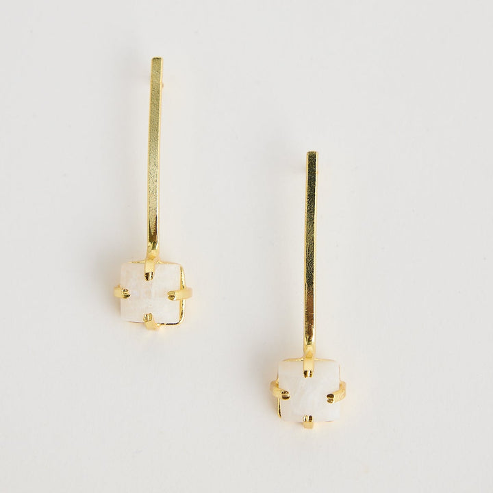 Pair of gold earrings with gemstones on a light gray background