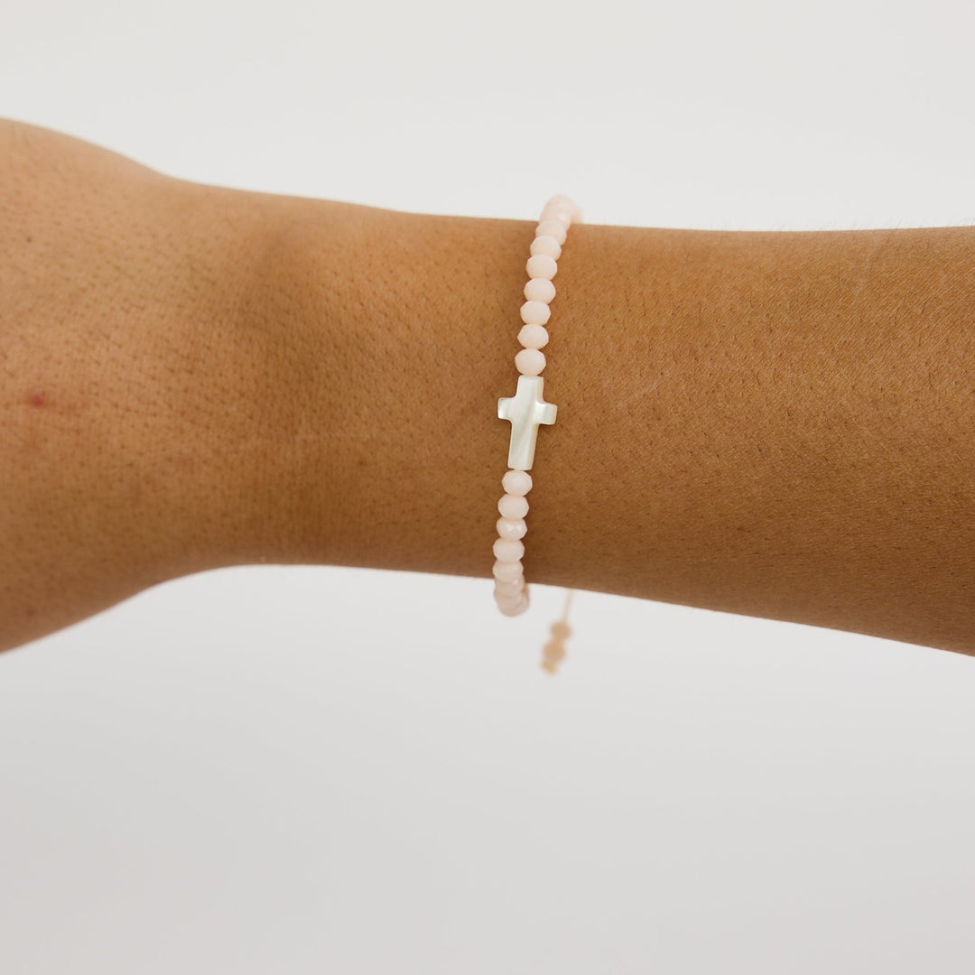 White beaded bracelet on a wrist against a plain background
