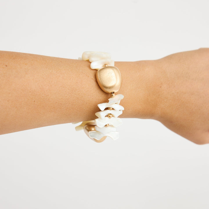 Gold and pearl bracelet on a wrist against a white background