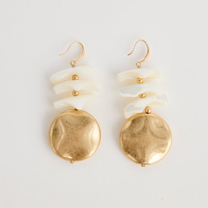Pair of gold and white earrings on a light gray background