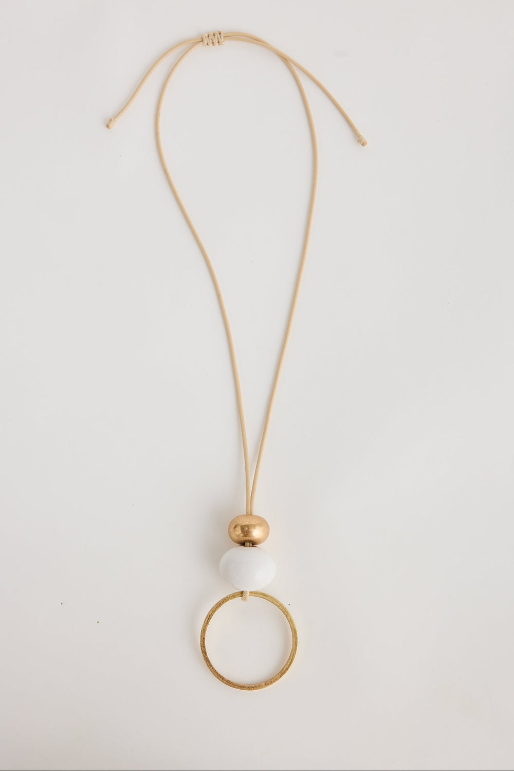 Gold necklace with a white pendant on a light gray background