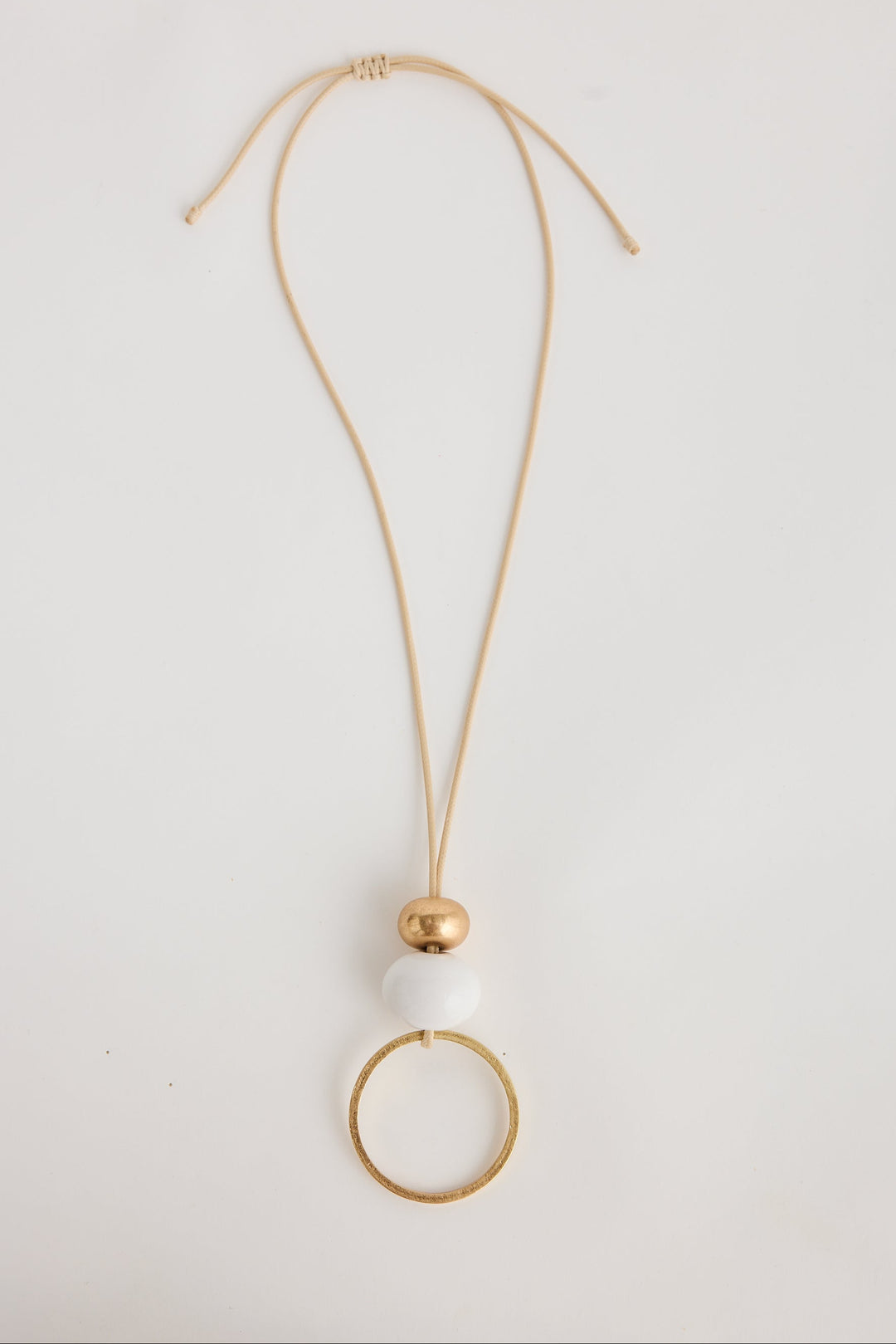 Gold necklace with a white pendant on a light gray background