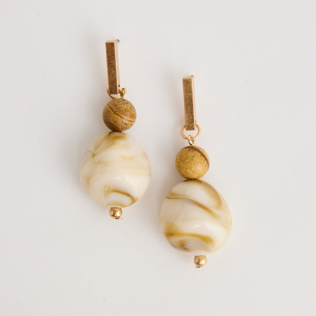 Pair of earrings with beige and gold beads on a light gray background