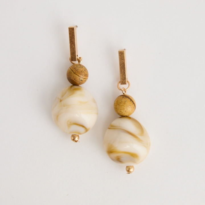 Pair of earrings with beige and gold beads on a light gray background
