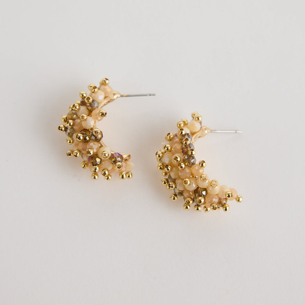 Gold floral hoop earrings on a light gray background