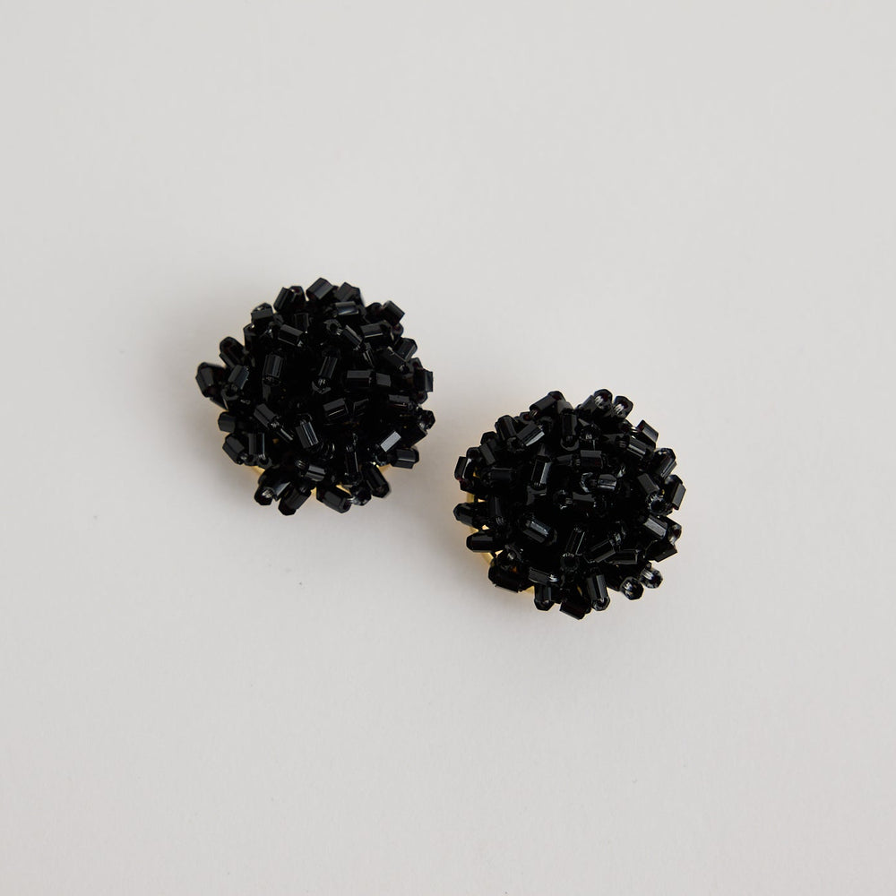 Pair of black stud earrings on a light gray background