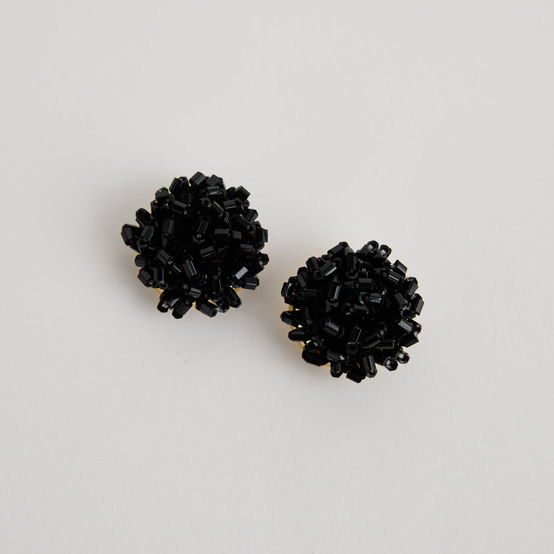 Pair of black stud earrings on a light gray background