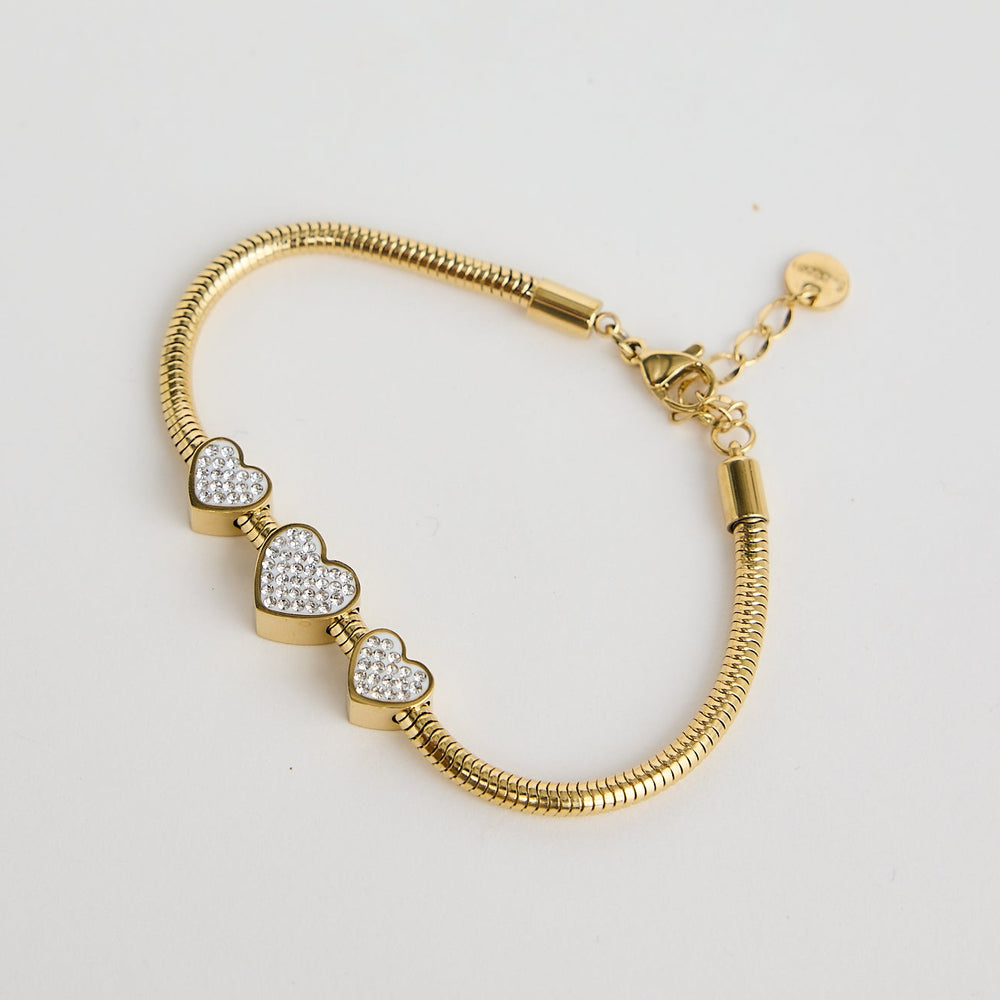 Gold bracelet with heart-shaped charms on a light gray background