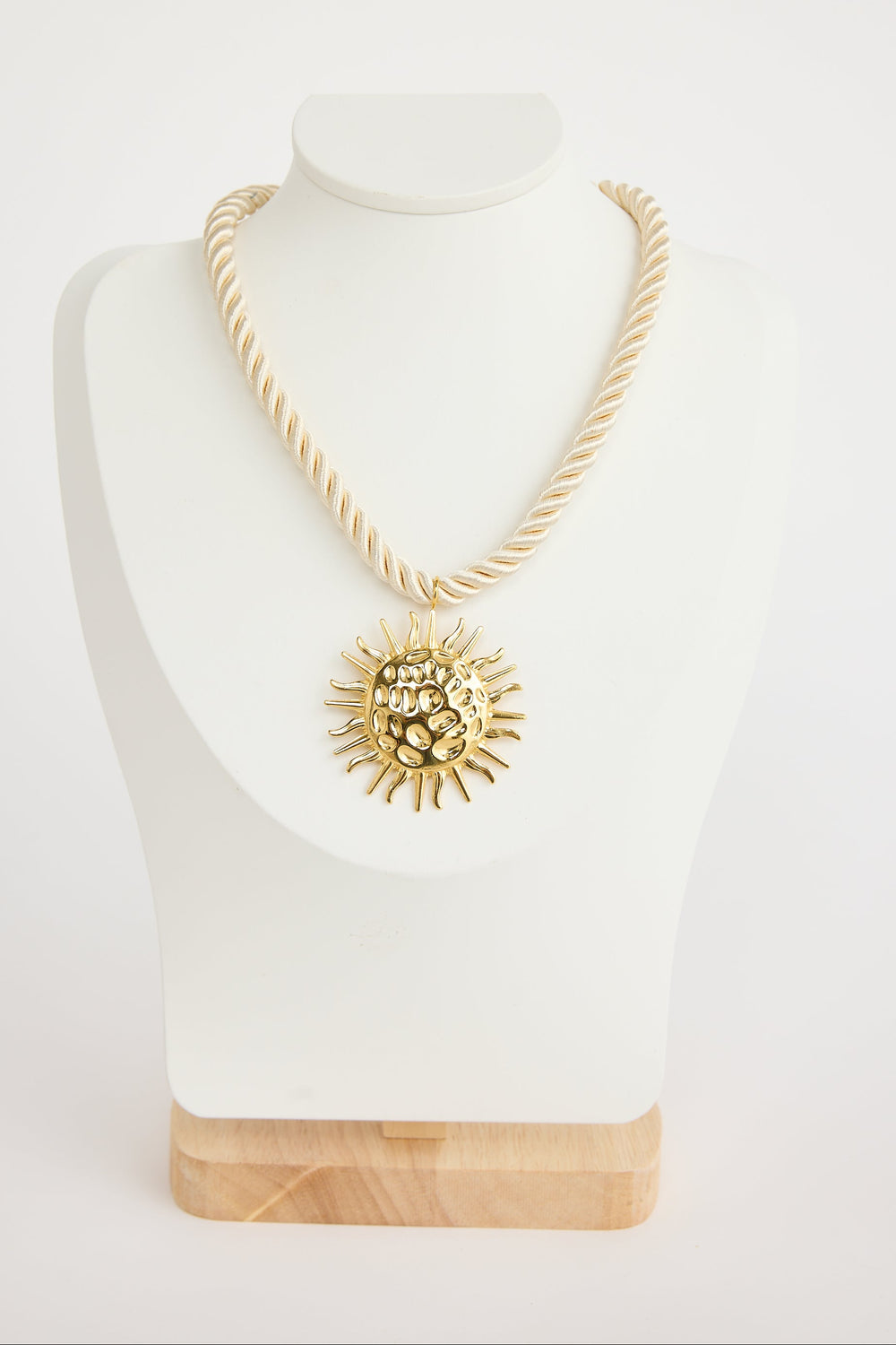 Gold necklace with a sunflower pendant on a mannequin bust against a white background
