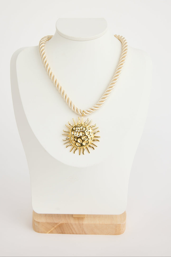 Gold necklace with a sunflower pendant on a mannequin bust against a white background