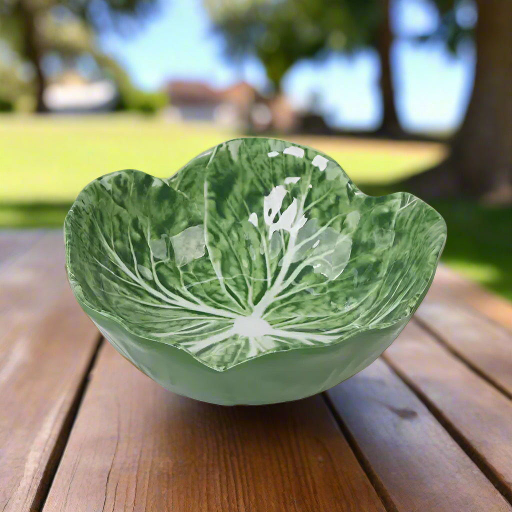 Green ceramic bowl shaped like a cabbage leaf on a light gray background