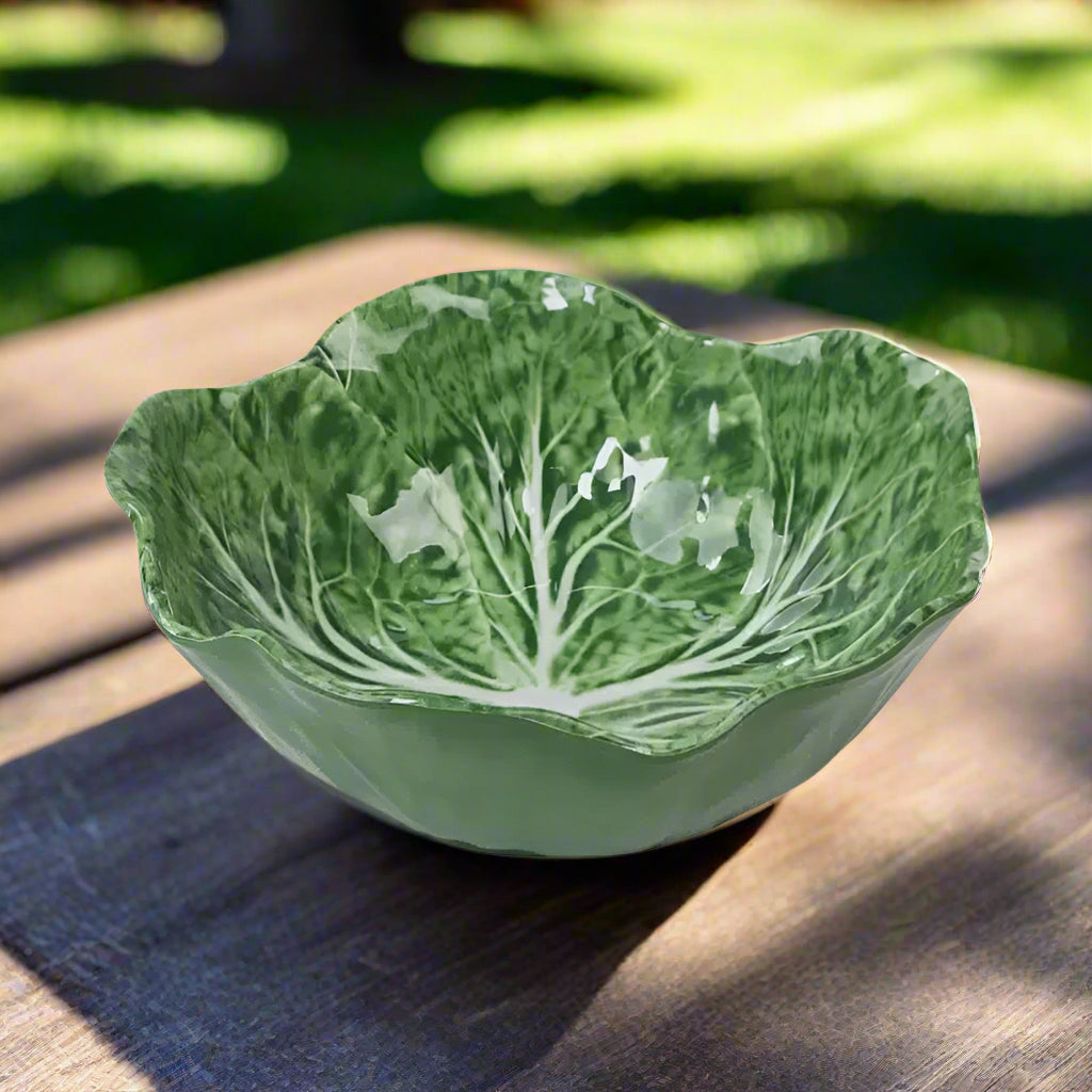 Green ceramic bowl shaped like a cabbage on a white background