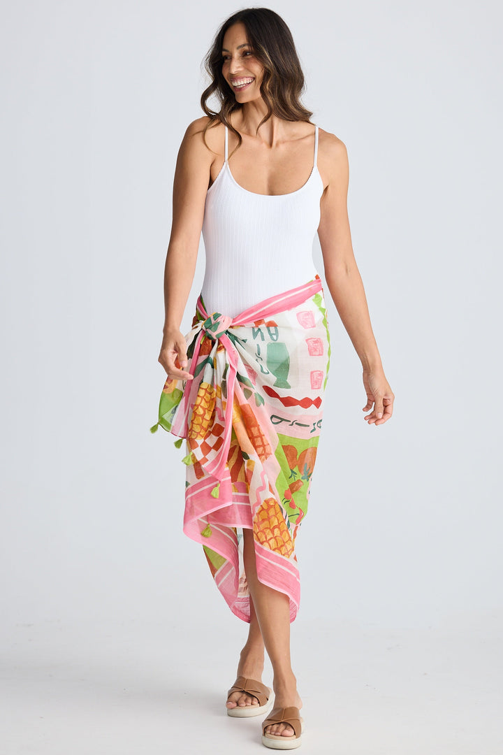 Woman wearing a colorful sarong over a white tank top on a white background