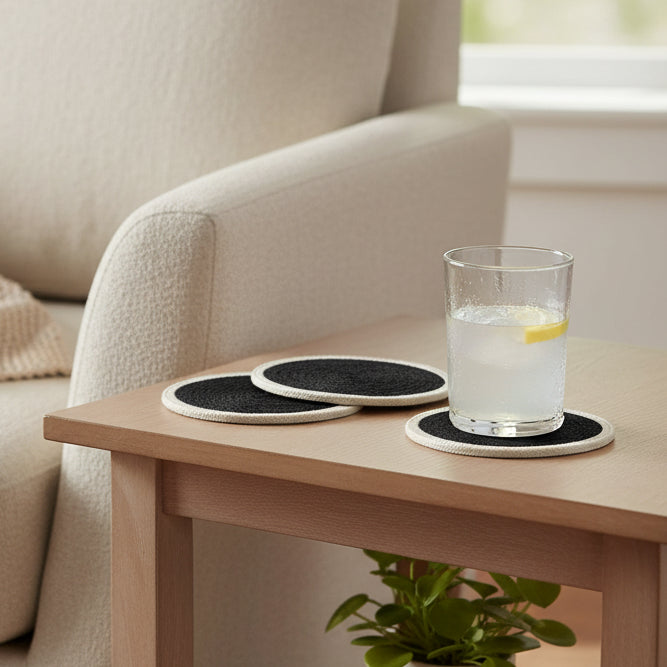 Four black round coasters with white edges on a white background