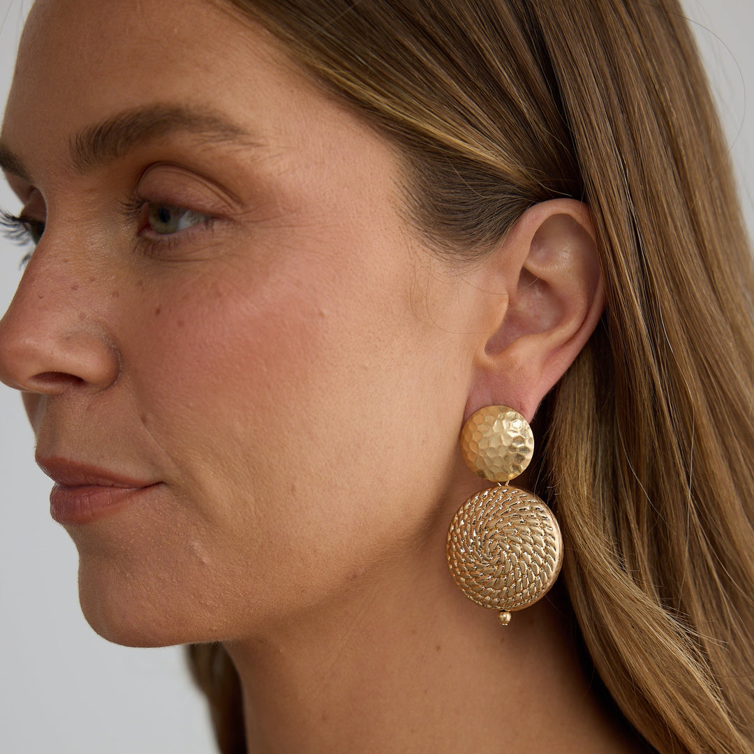 Close-up of a woman wearing gold earrings with a neutral background