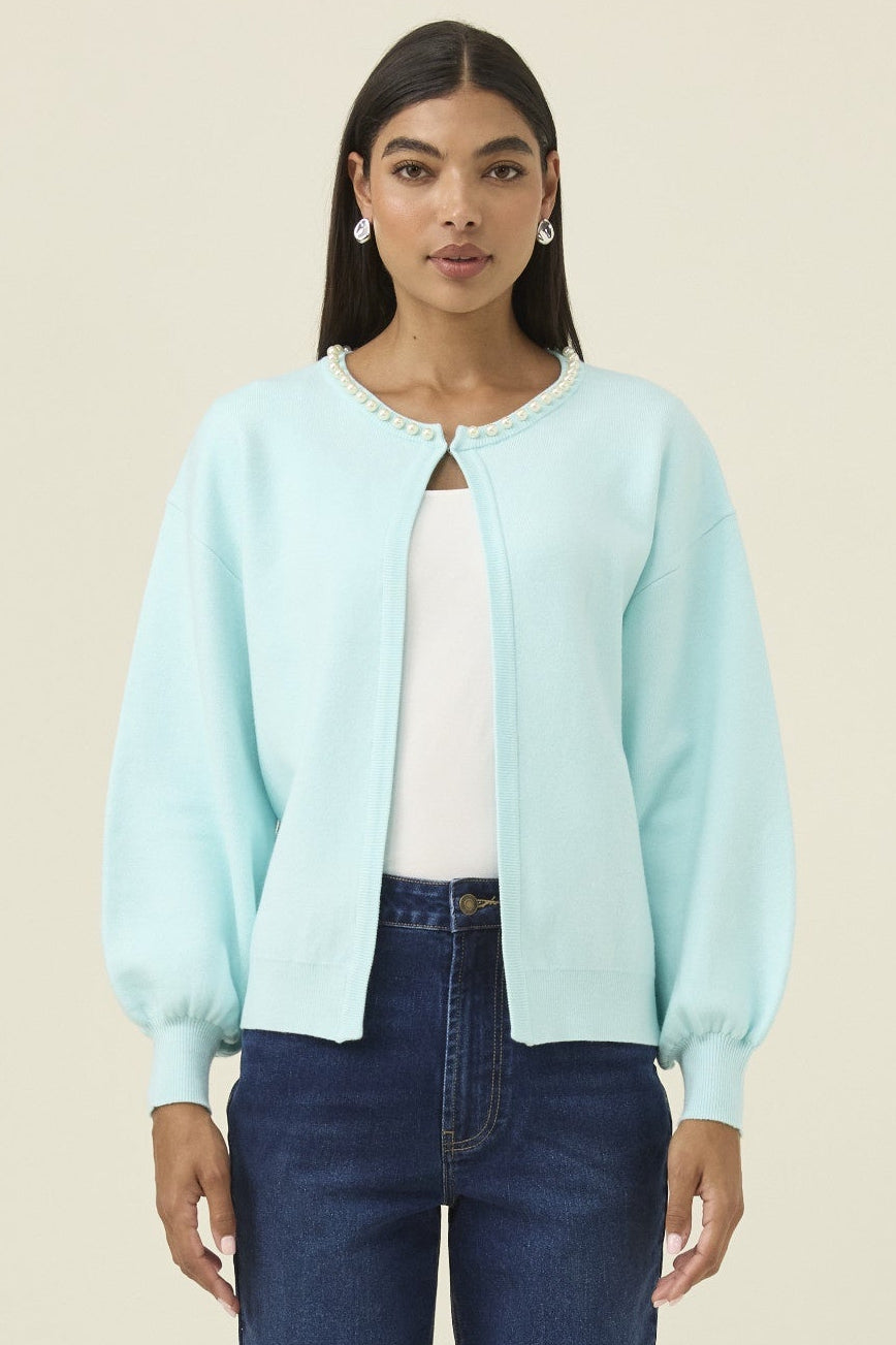 Woman wearing a light blue jacket and dark blue jeans on a beige background