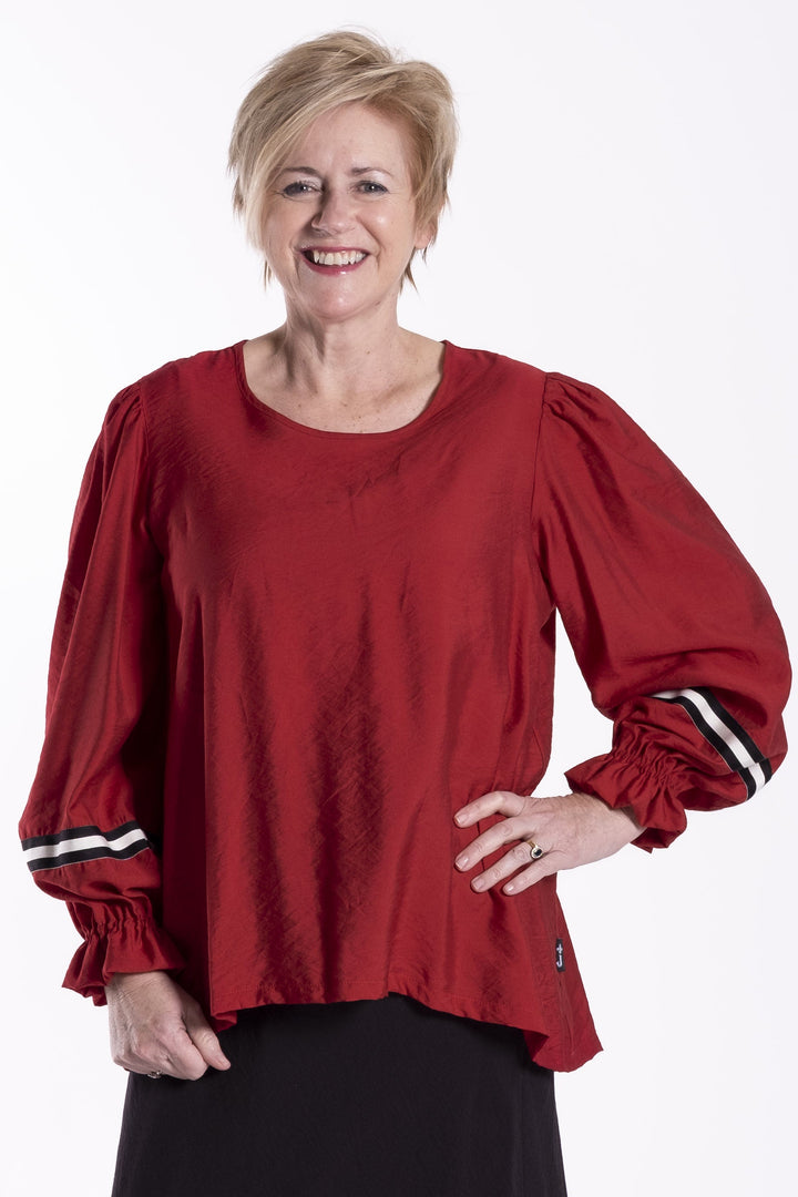 Person wearing a red jellicoe Claire  top and black skirt on a white background