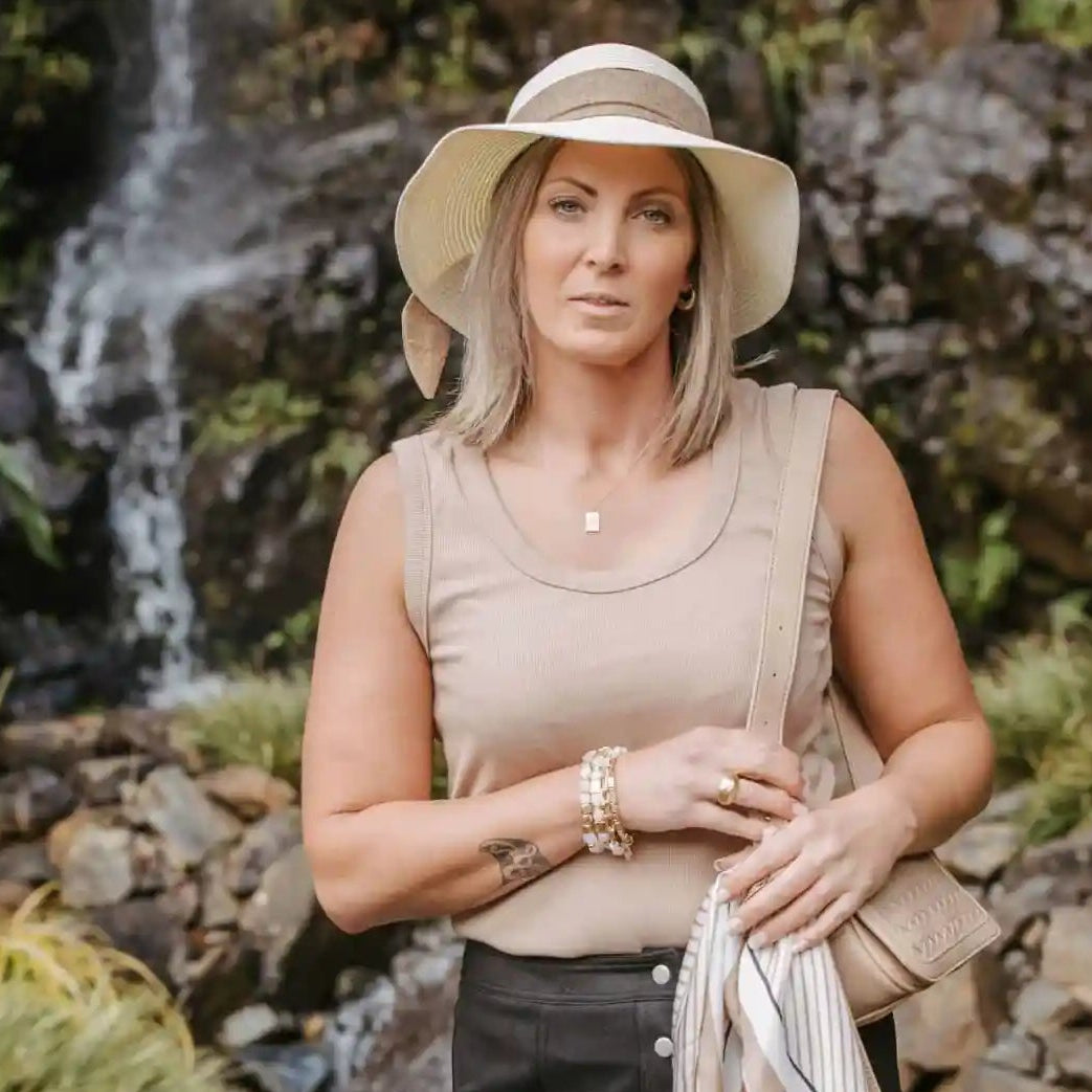 Woman standing outdoors with a waterfall in the background