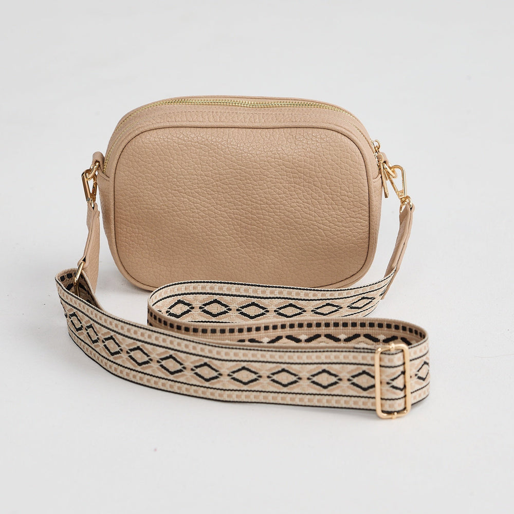 Beige crossbody bag with a patterned strap on a light gray background