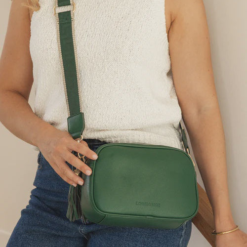 Person wearing a green crossbody bag with a neutral background