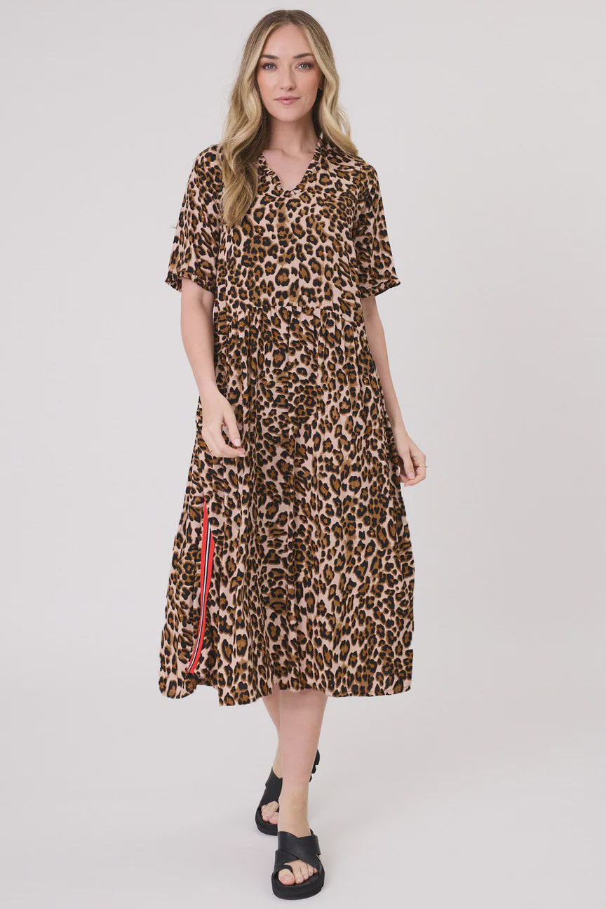 Woman wearing a leopard print dress with red accents on a white background