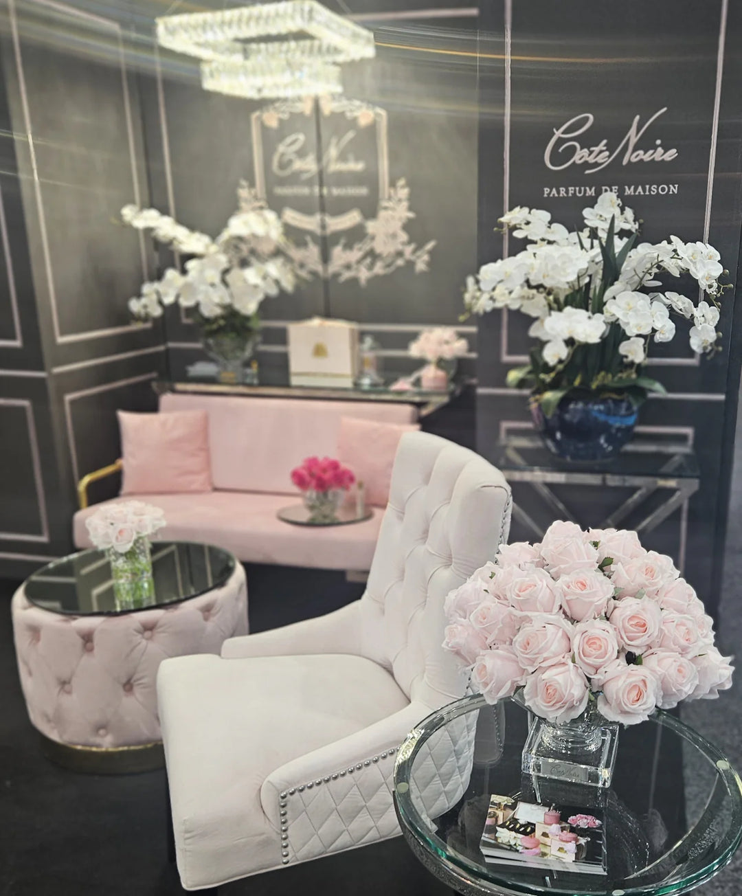 Luxurious interior with white armchair, pink sofa, and floral arrangements in a stylish room.