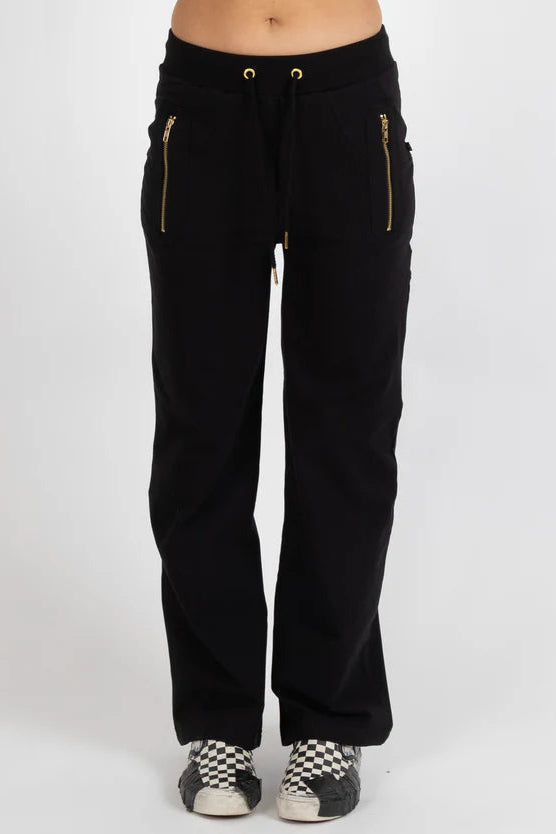 Black pants with gold zippers worn by a person on a white background