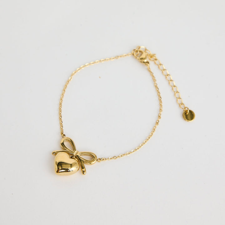 Gold bracelet with a bow charm on a light gray background