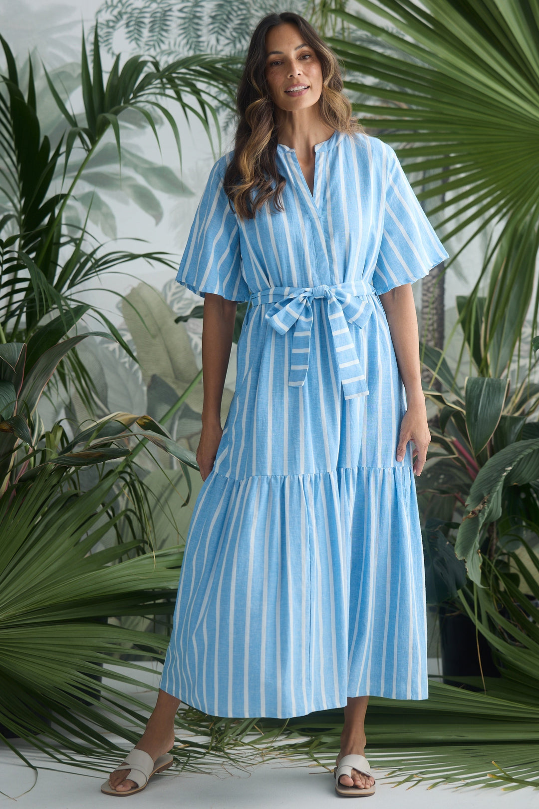 Woman wearing a blue striped dress standing in front of green plants