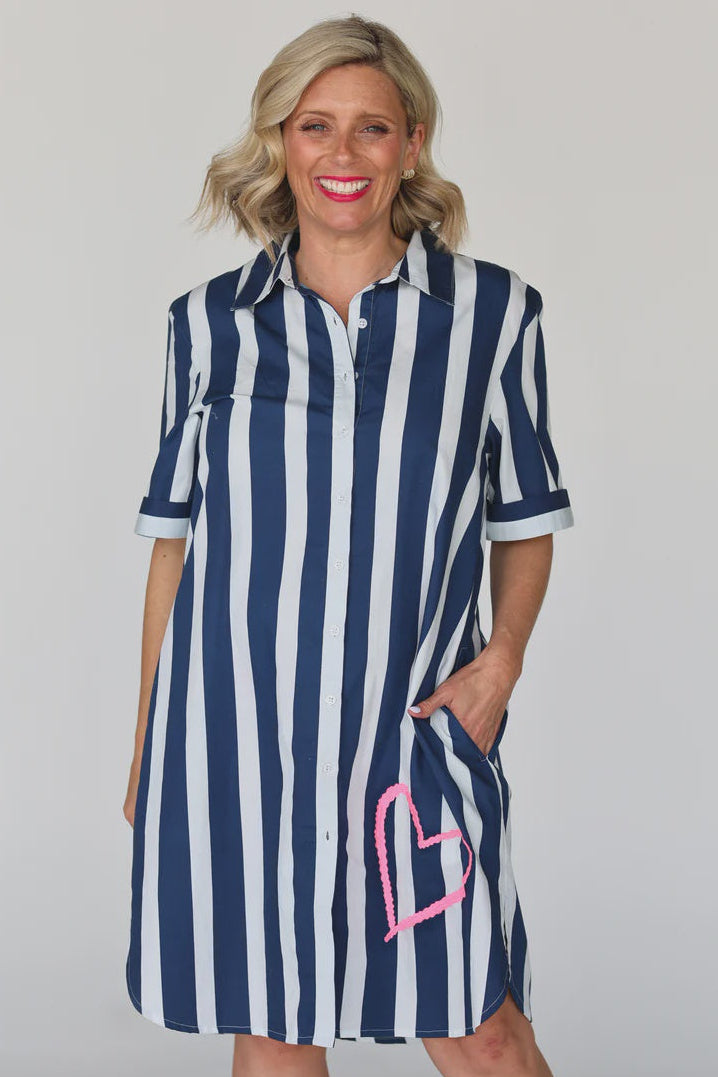Woman wearing a navy and white striped dress with a pink heart design on a plain background