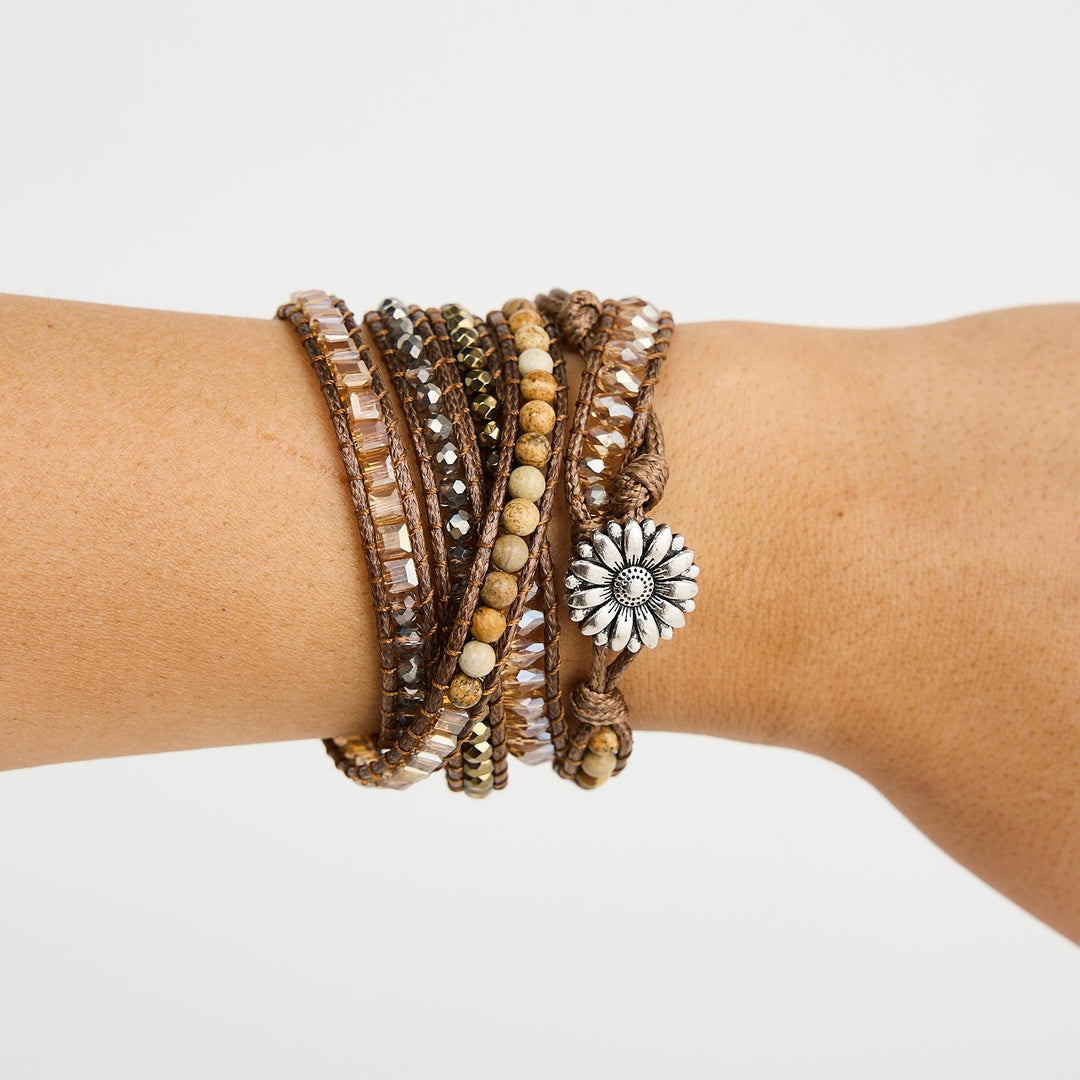 Stacked bracelets on a wrist against a plain background