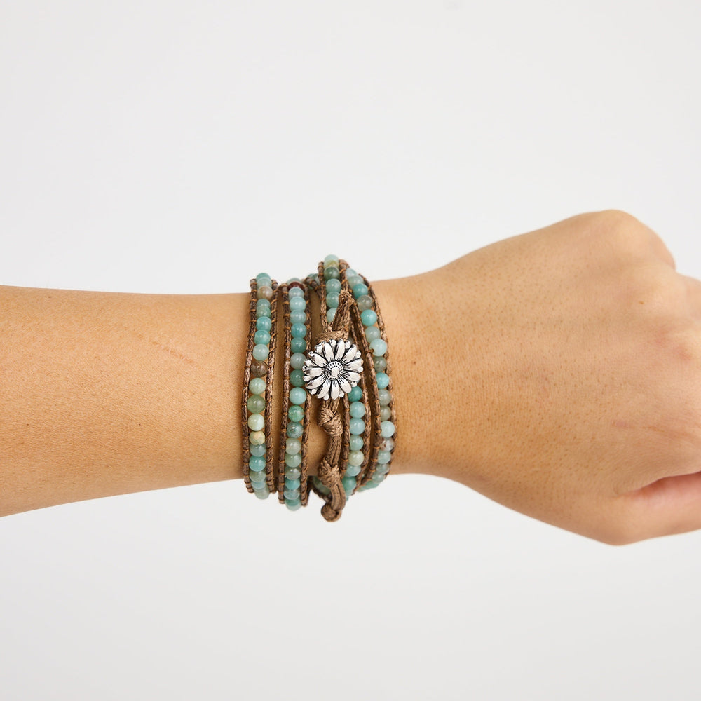 Hand wearing multiple beaded bracelets on a plain background