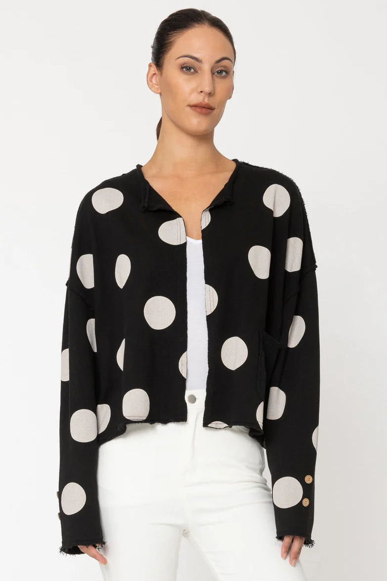 Woman wearing a black blouse with white polka dots and white pants on a white background