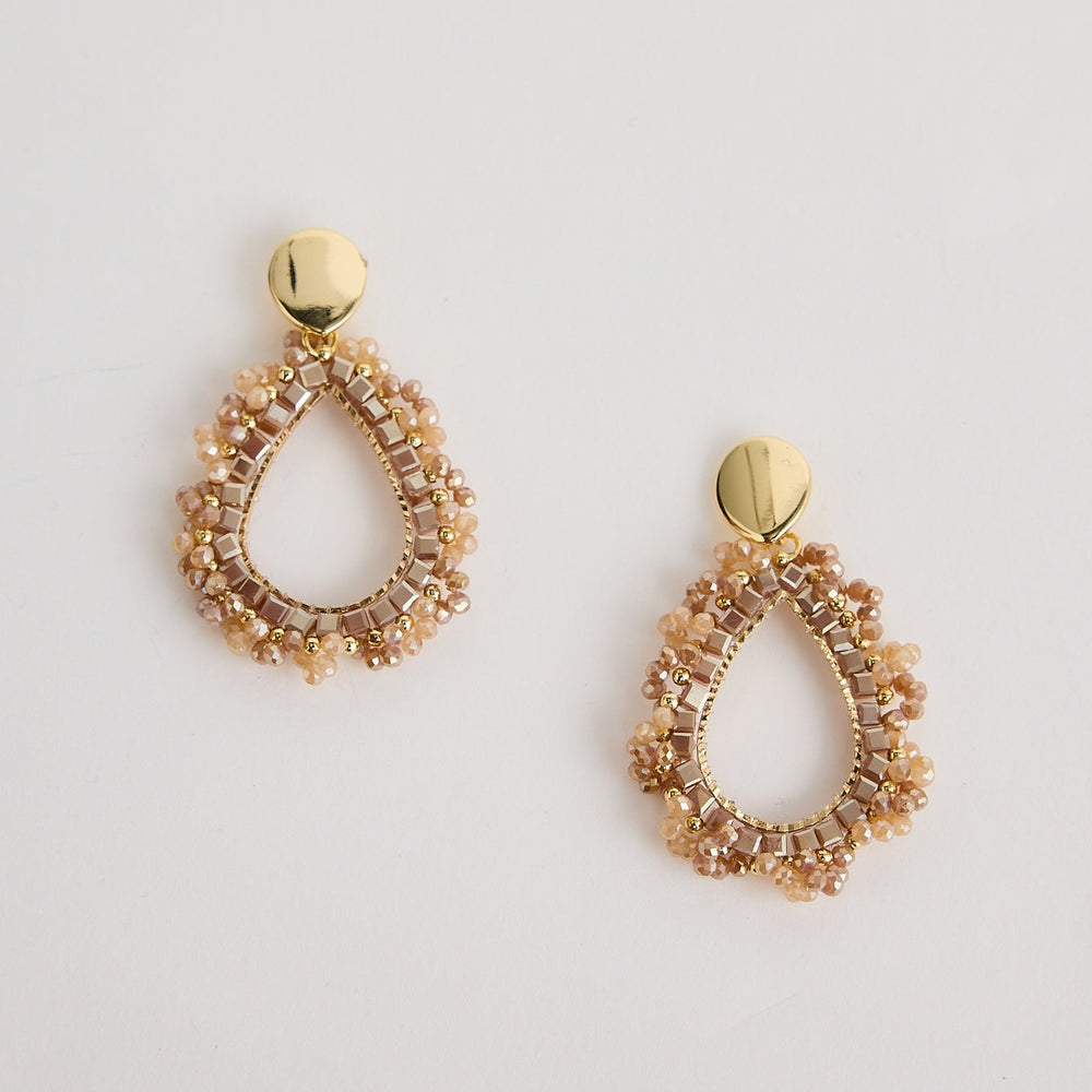 Pair of gold teardrop earrings on a light gray background