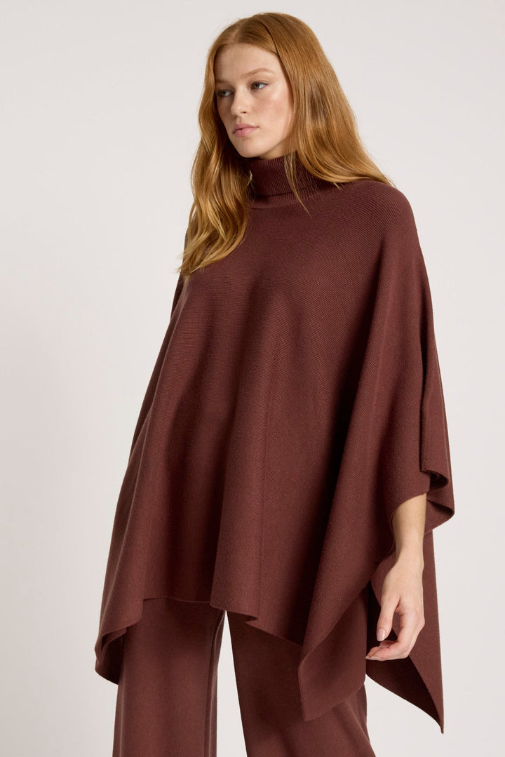 Woman wearing a brown poncho and pants on a white background