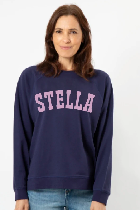 Woman wearing a navy blue sweatshirt with 'STELLA' printed in pink on a white background