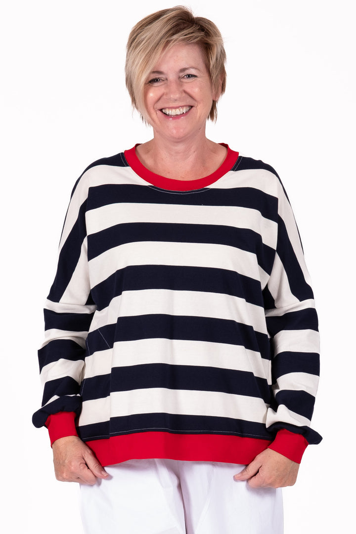 Person wearing a black and white striped sweater with red trim on a white background