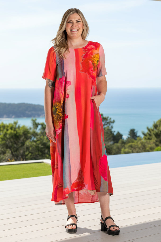 Woman wearing a colorful Deeanne Hobbs dress with a patterned jacket on a white background