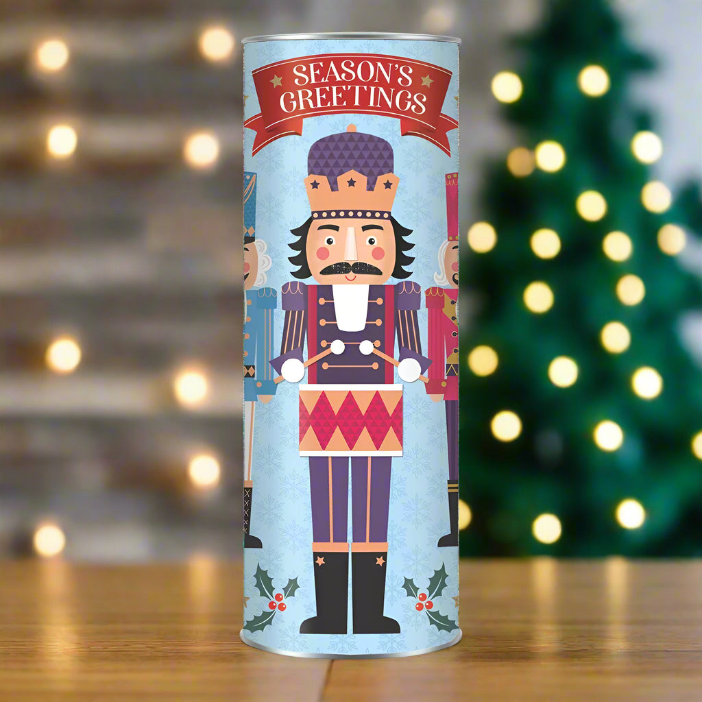 Decorative cylindrical COOKIE TUBE with nutcracker design and 'Season's Greetings' text on a white background