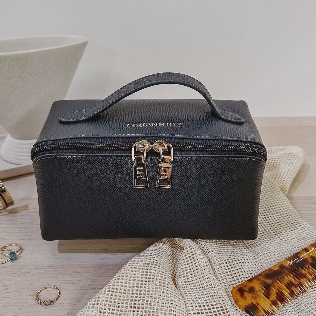 Navy Louenhide cosmetic case on a light wooden surface with a white bowl and accessories.