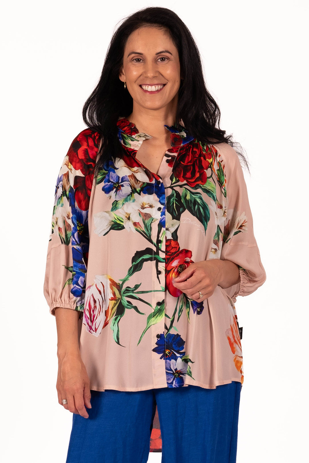 Woman wearing a floral blouse and blue pants on a white background