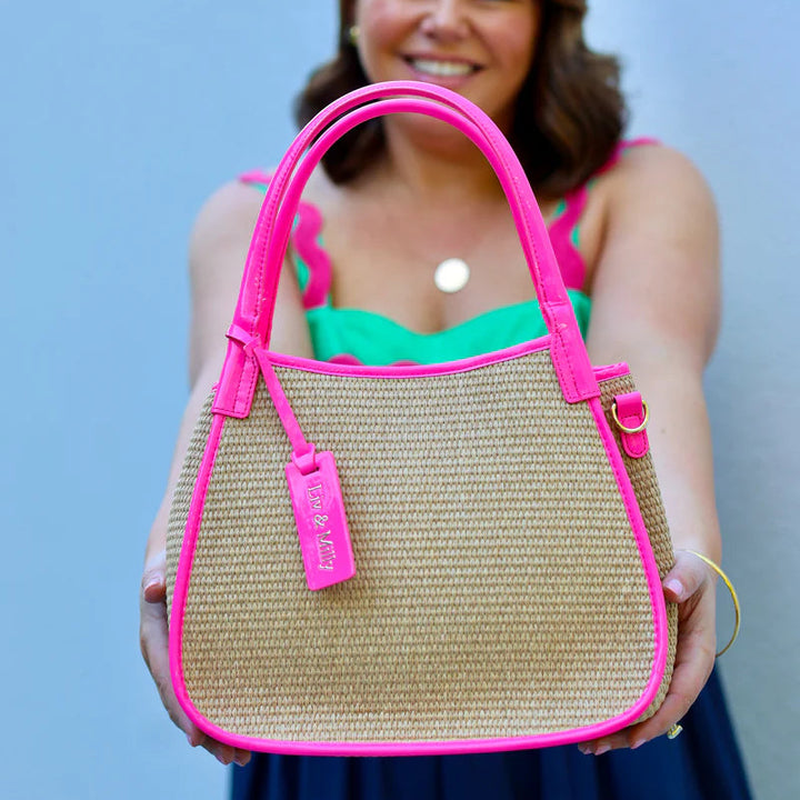 Woman holding a straw handbag with pink accents against a blue background