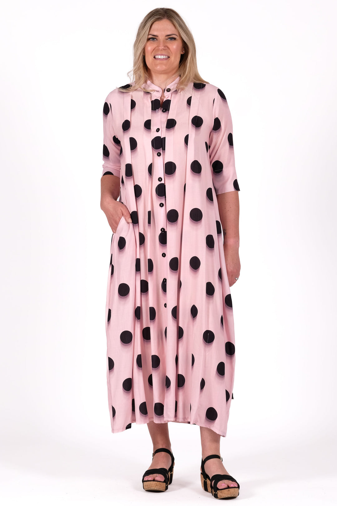 Woman wearing a pink dress with black polka dots on a white background