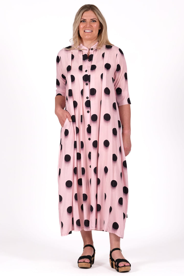 Woman wearing a pink dress with black polka dots on a white background
