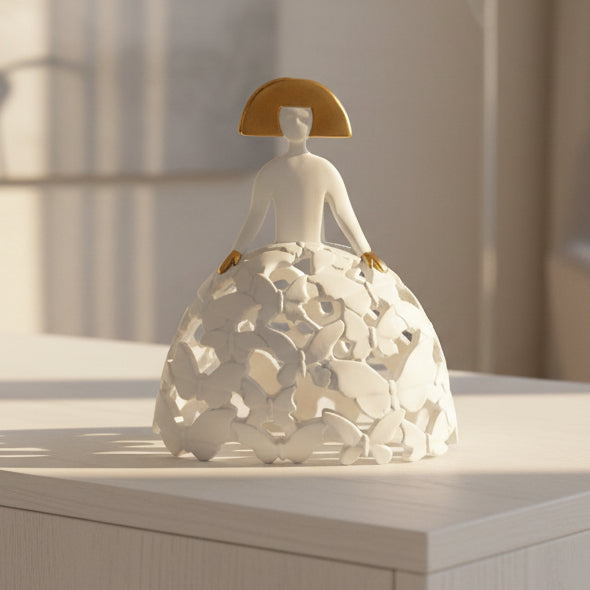 White ceramic figure with gold accents on a light gray background