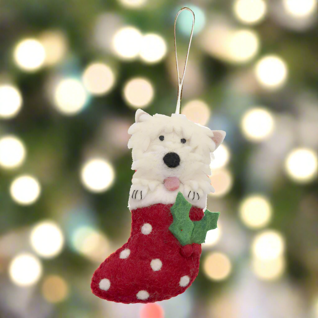 Dog-shaped Christmas ornament in a red stocking with white polka dots on a white background