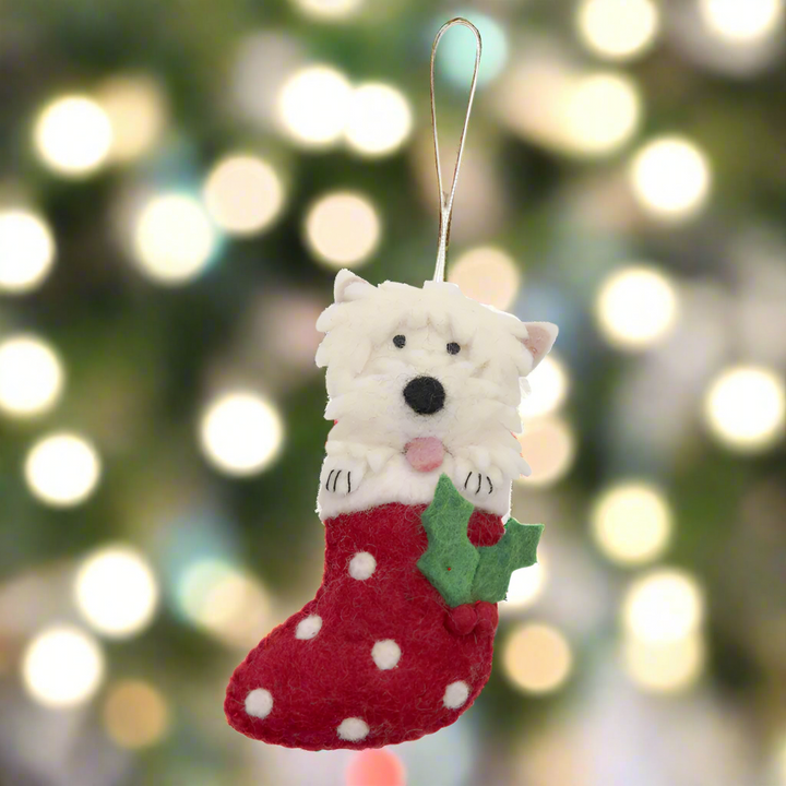 Dog-shaped Christmas ornament in a red stocking with white polka dots on a white background