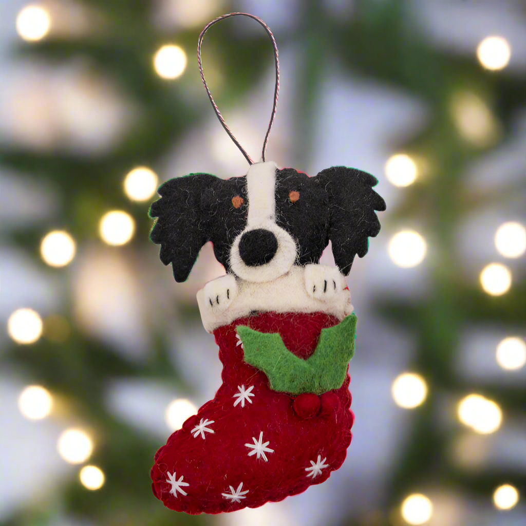 Felt ornament of a dog in a red stocking with white snowflakes on a white background
