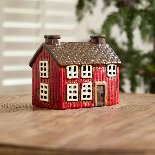 Small red house figurine on a wooden surface with a blurred background