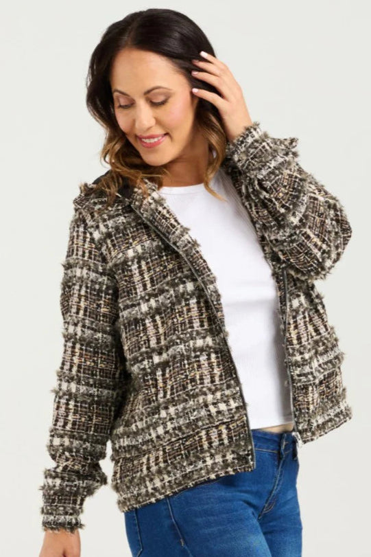 Woman wearing a patterned jacket over a white shirt and blue jeans on a white background